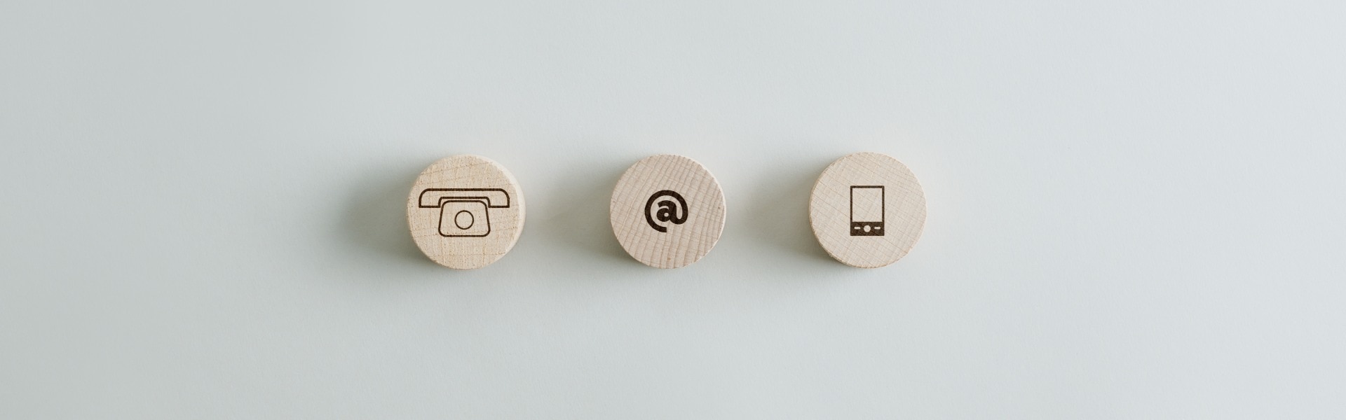 Drei Holzkreise mit Kontakt- und Kommunikationssymbolen