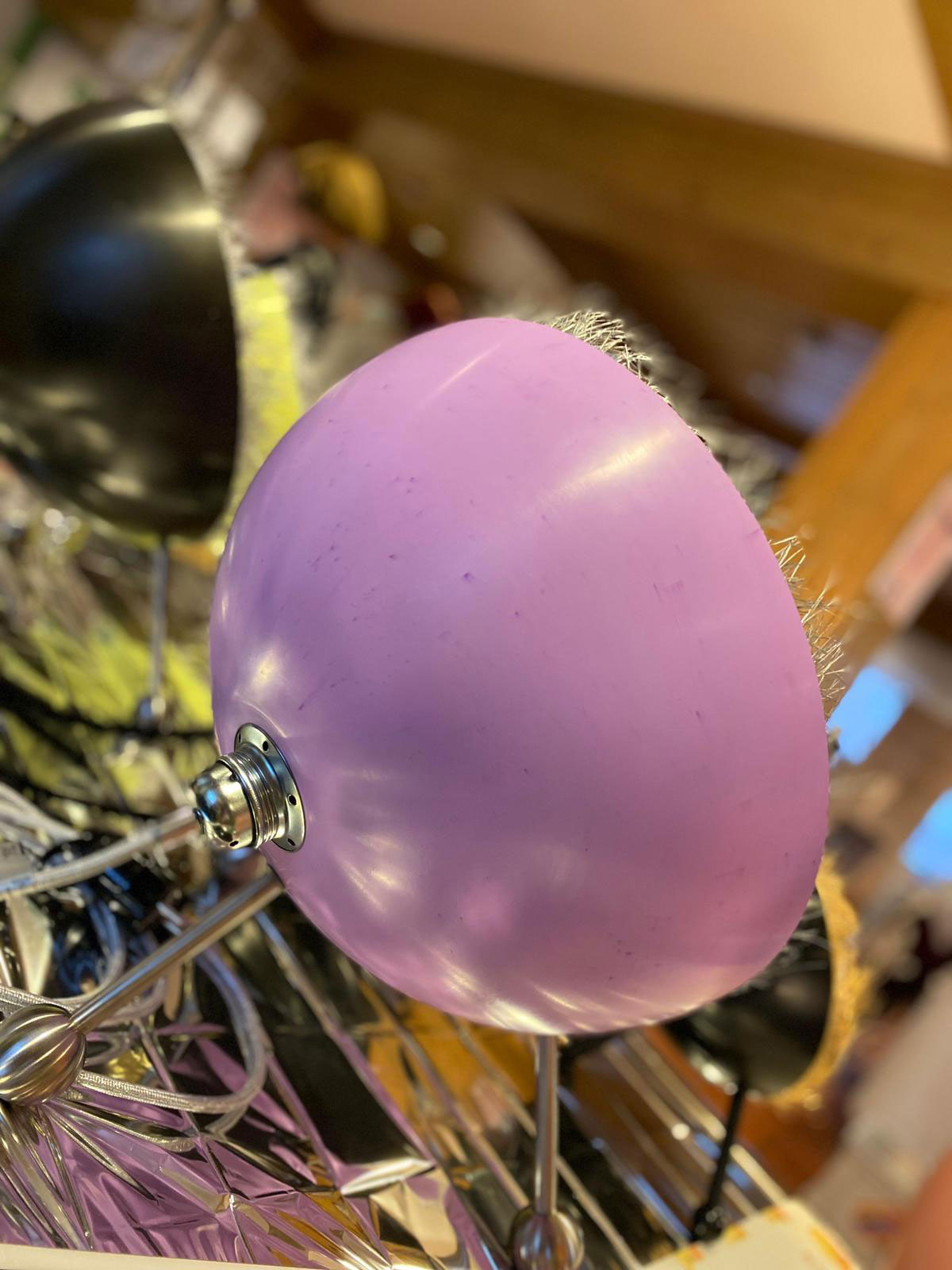 Eine lila Lampe mit silbernem Ständer und schwarzen Details steht auf einem Tisch