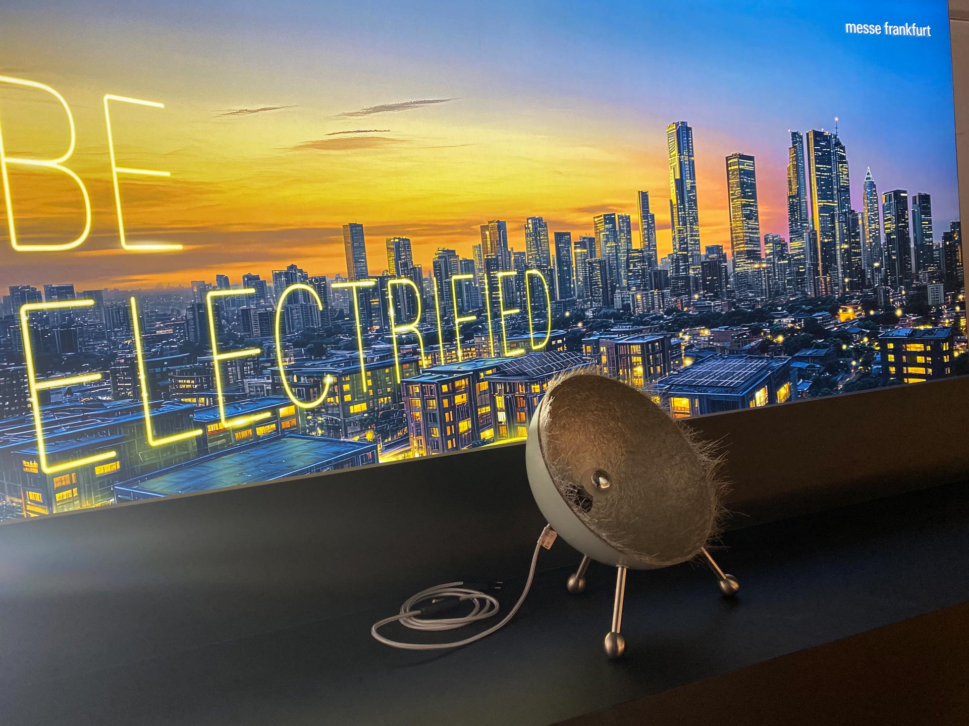 Skyline bei Sonnenuntergang, davor metallisches Objekt mit Kabel, blaugelb
